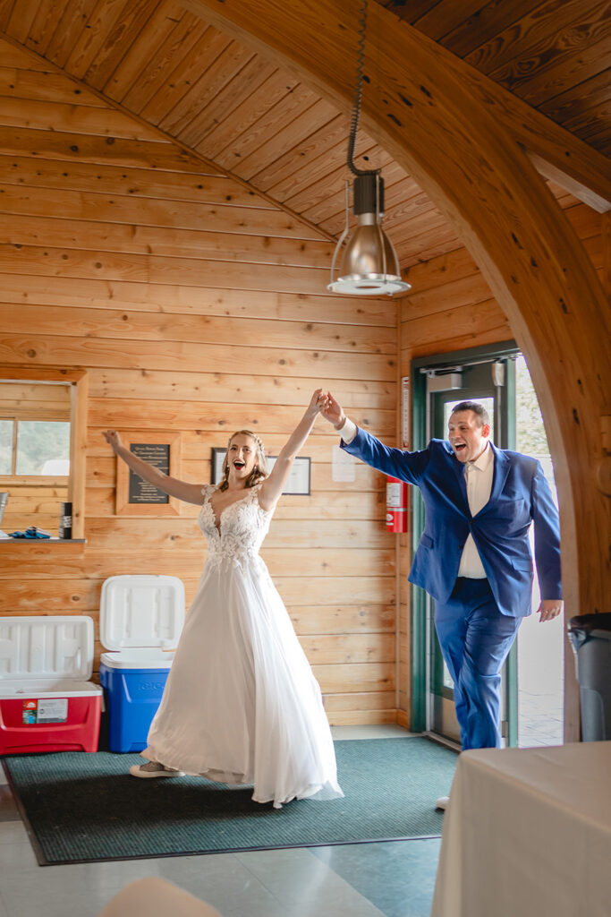 Bride and Groom lift their handles in celebration as they walk through the door into their venue for their grand entrance