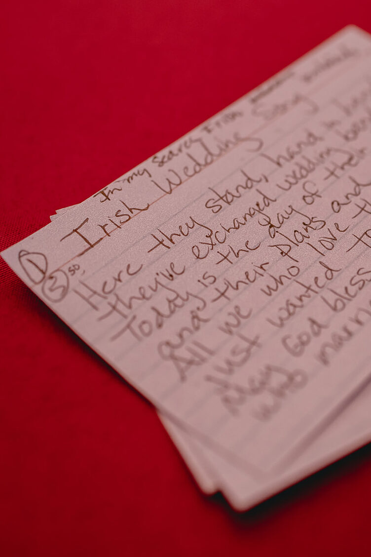 Close up of an index card on a red tablecloth of the Irish Wedding Song lyrics sung before dinner