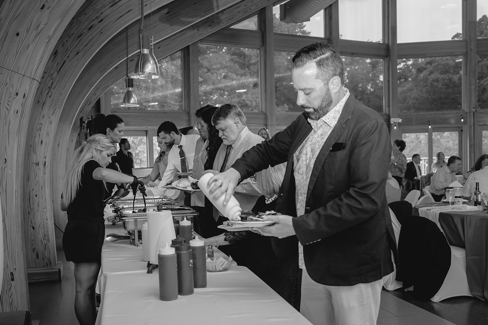 black and white shot of guest putting sauce on his plate in the buffet line