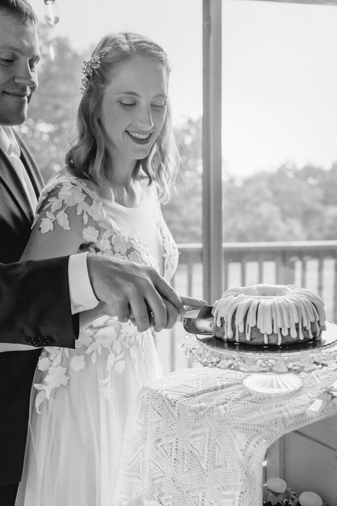 Black and white tight shot of newlyweds cutting wedding bundt cake