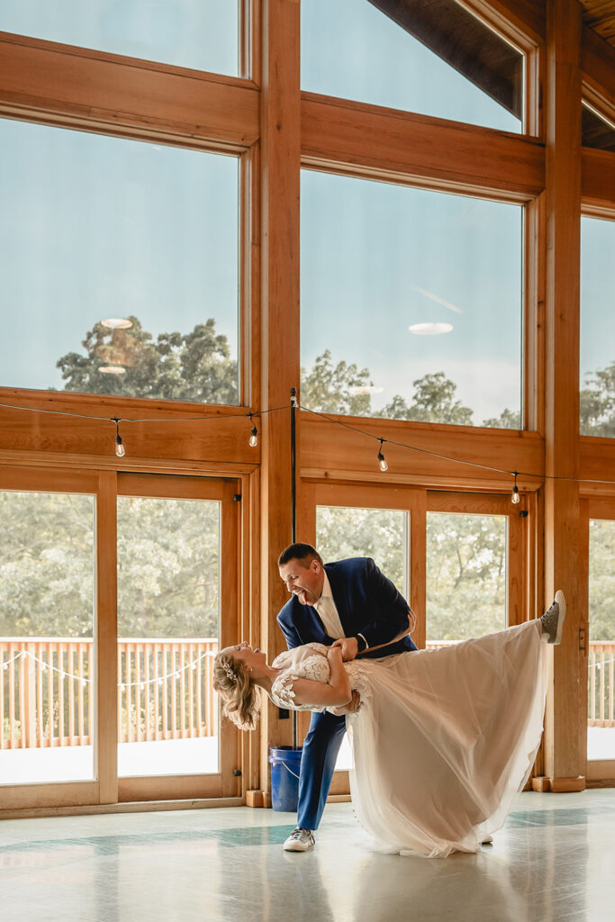 bride and groom share a first dance in front of window wall in Quail Ridge Lodge