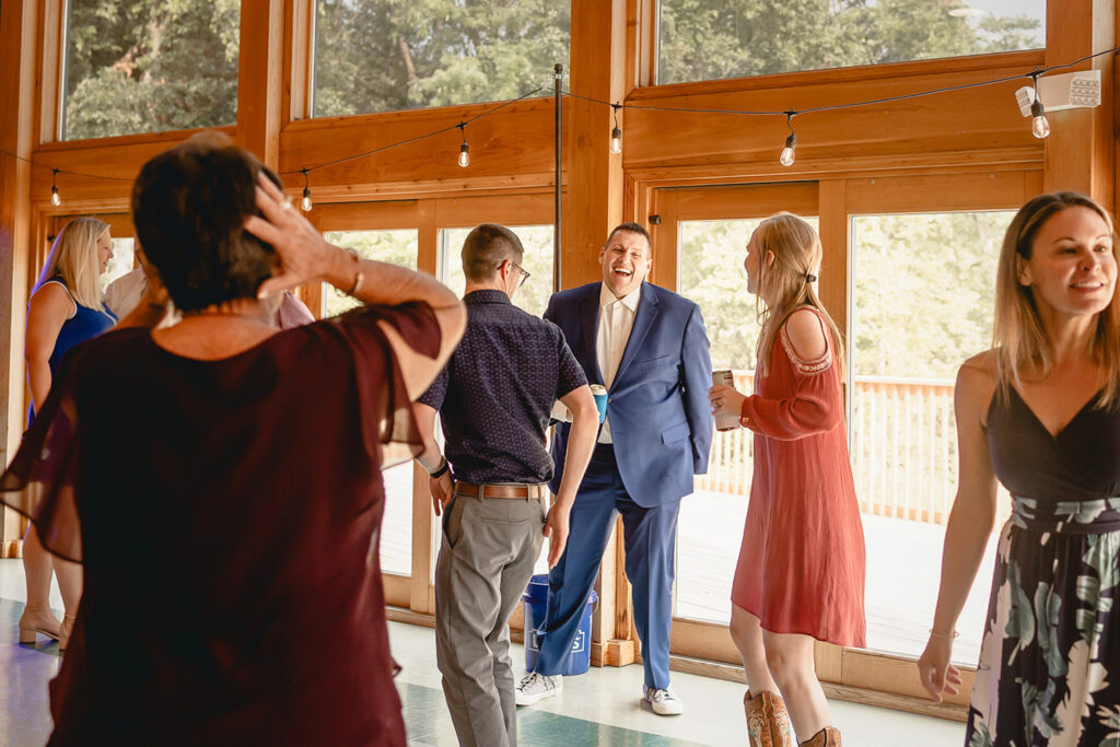Candid shot of groom laughing on the dance floor with wedding guests