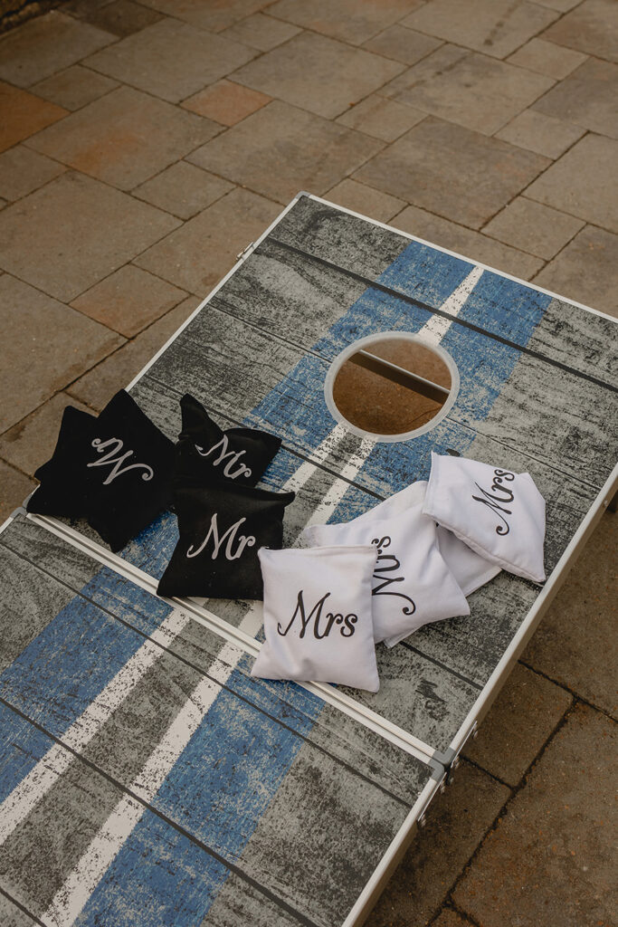 black and white bags that say 'Mr' and 'Mrs' sit atop a cornhole board