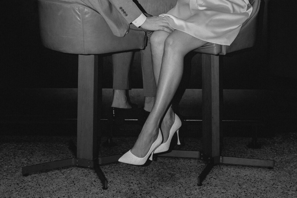 black and white artsy shot of couples legs interwined while seating on bar stools