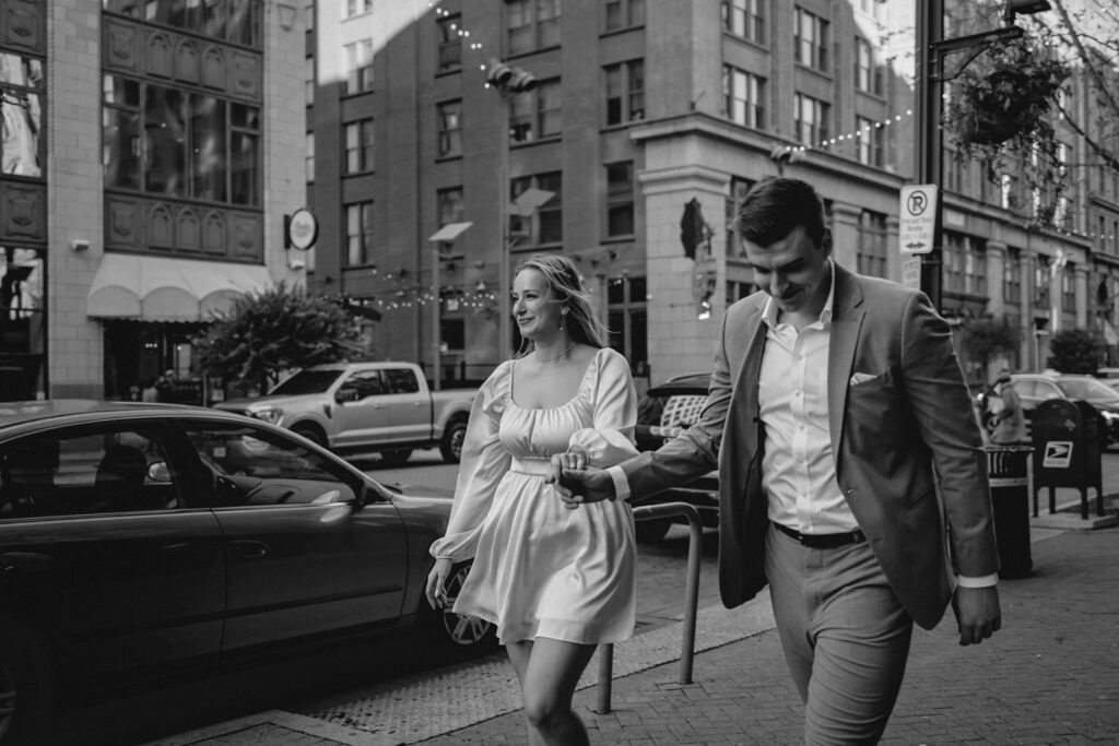 candid shot of couple holding hands and walking down a busy downtown street