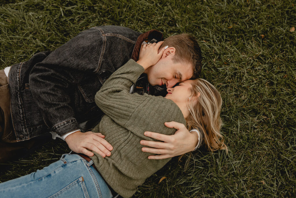 aerial shot of couple cuddling close in the grass, foreheads together