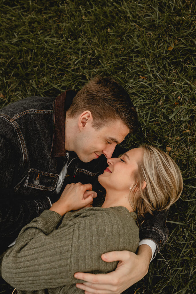 aerial shot of couple cuddling close in the grass, noses together