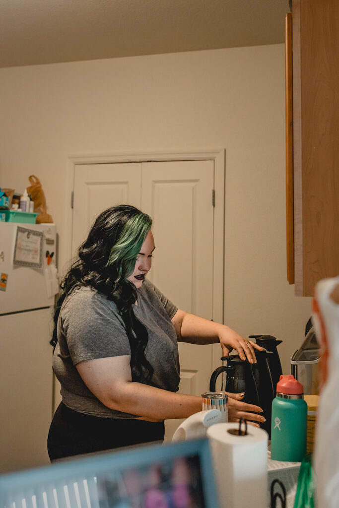 young bride with a streak of colored green hair prepares hot cocoa in iher apartment kitchen