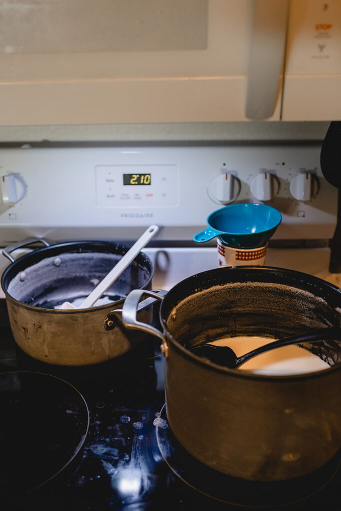 two pots of hot cocoa ingredients simmer on a stove