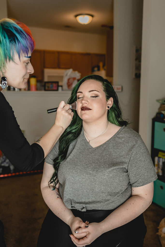 bride smiles with eyes closed as she gets her makeup done 
