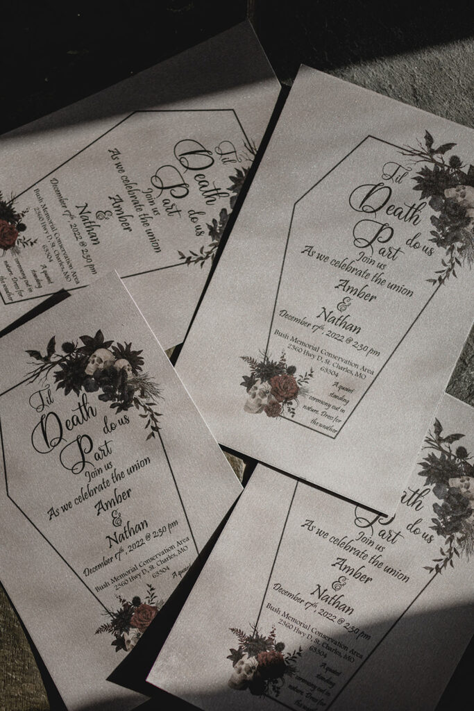 Gothic-inspired silver and black wedding invites splayed across the frame