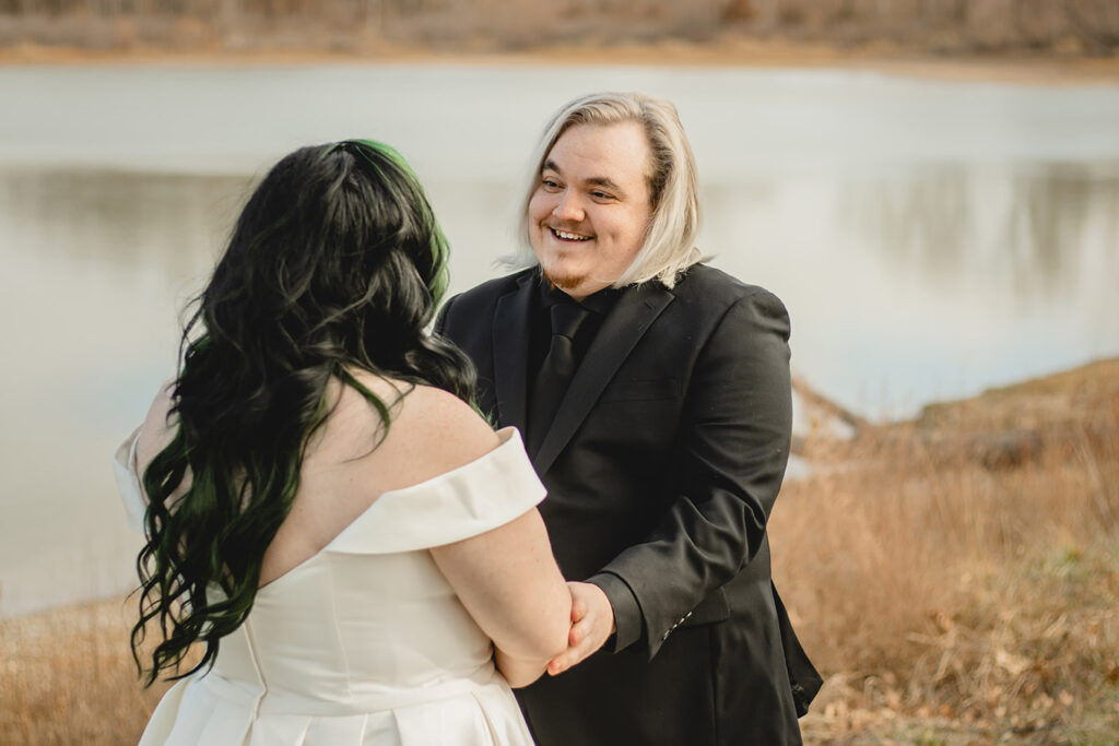 groom looking lovingly at his bride for the first time as he reaches out to hold her arms 