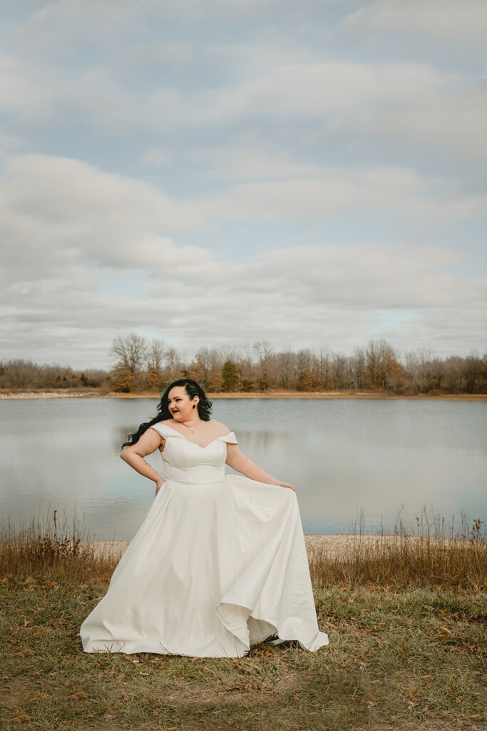 far shot of bride tossing her dress in front of a moody winter lake scene