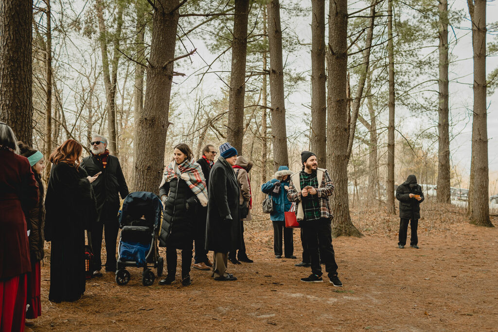candid shot of a group of people in winter gear huddled in a pine grove