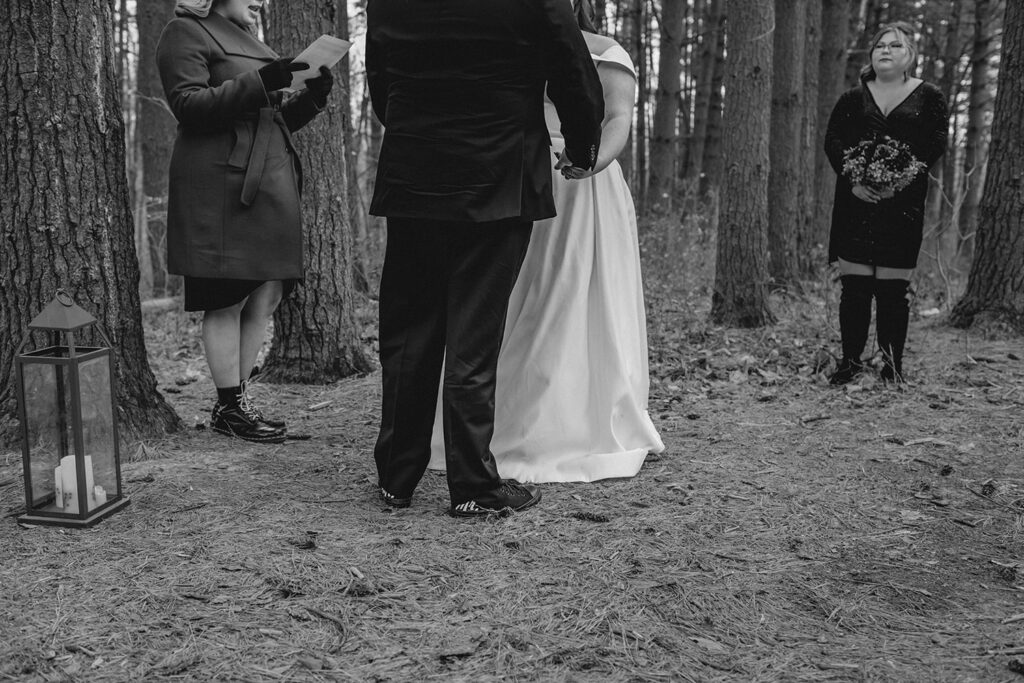 detail shot of bride and groom holding hands from the waist down