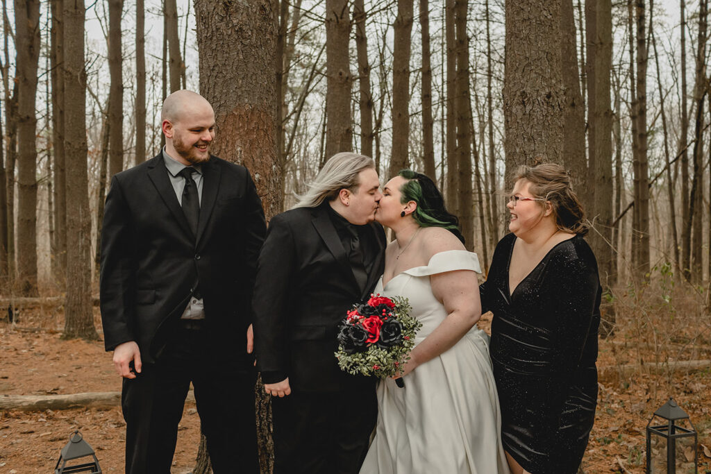 bride and groom share a kiss as their best man and maid of honor look on with smiles