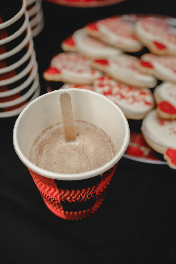 close up of hot chocolate bomb dissolving into a plaid black and red disposable cup