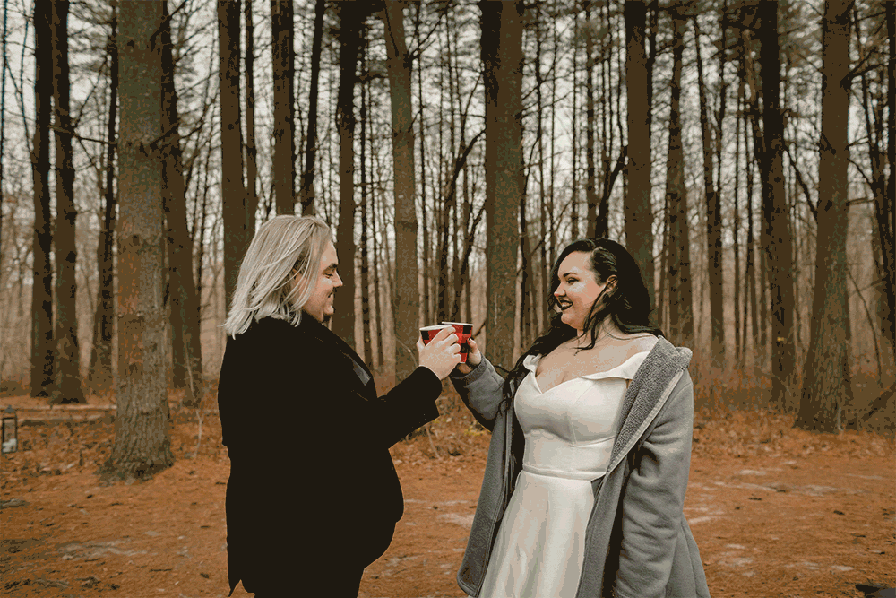 gif or bride and groom in a forest taking a a drink of hot chocolate before sharing a kiss
