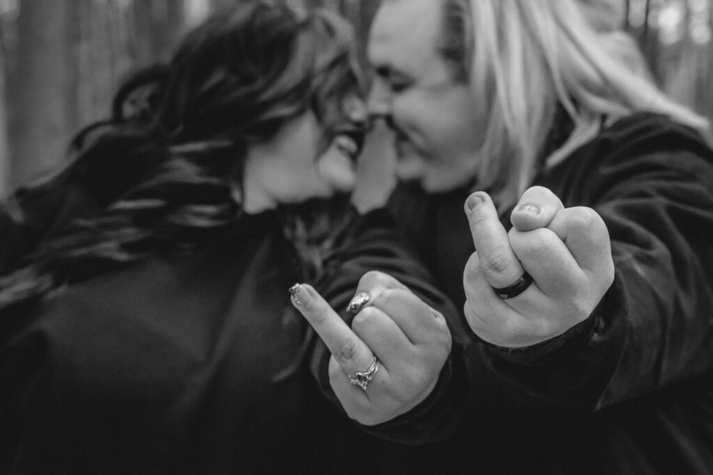 black and white shot of out of focus bride and groom leaning in for a kiss with ring fingers extended out toward the camera in focus