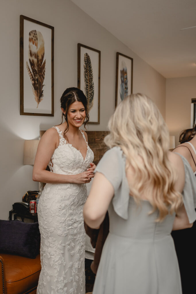 Bride smiling while looking at her bridesmaid in her new dress