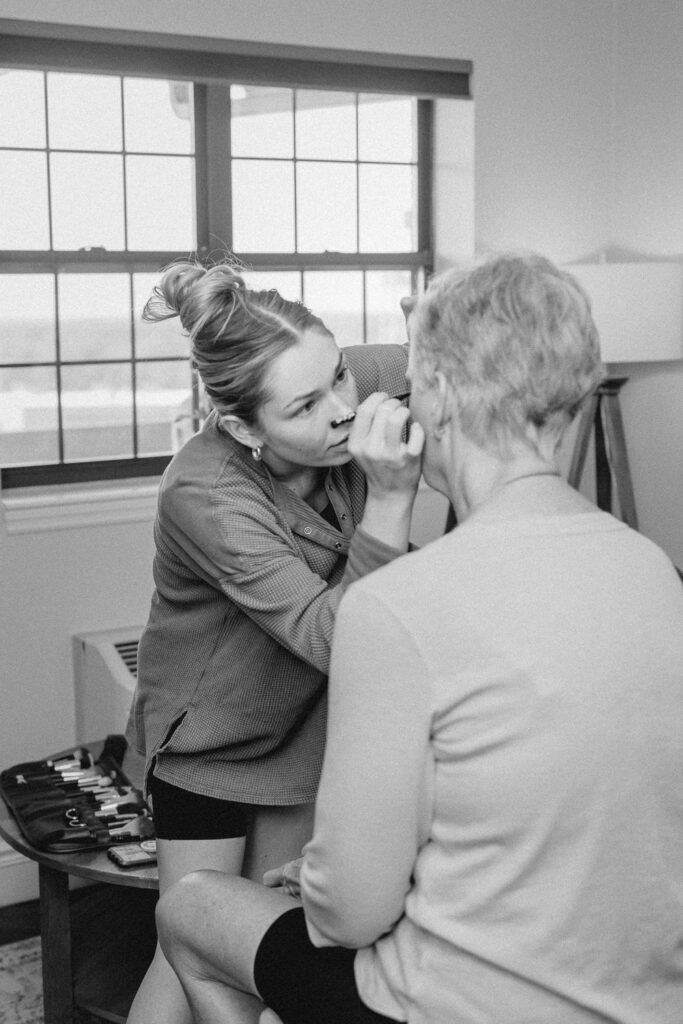 Make up artist applying make up to mother of the bride before wedding ceremony