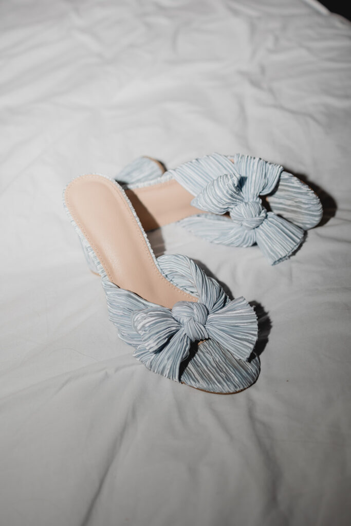 A brides blue shoes resting on a bed