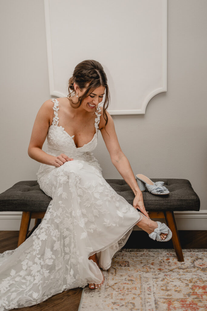 Bride putting on her new shoes while sitting on a bench.