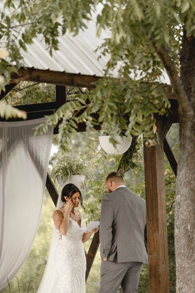 Bride and groom performing private vows in a lakeside gazebo
