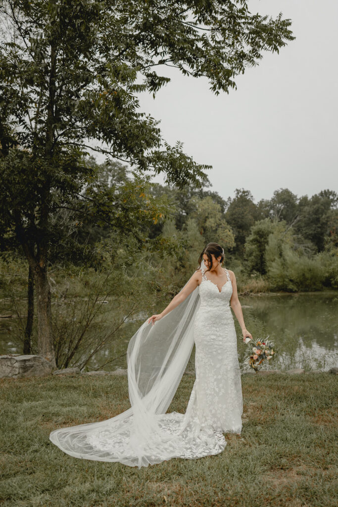 Bride plays with her long vail in front of lost hill lake.