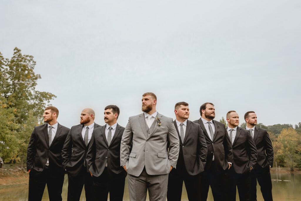 Groomsmen and groom posing in flying v pattern at lost hill lake.