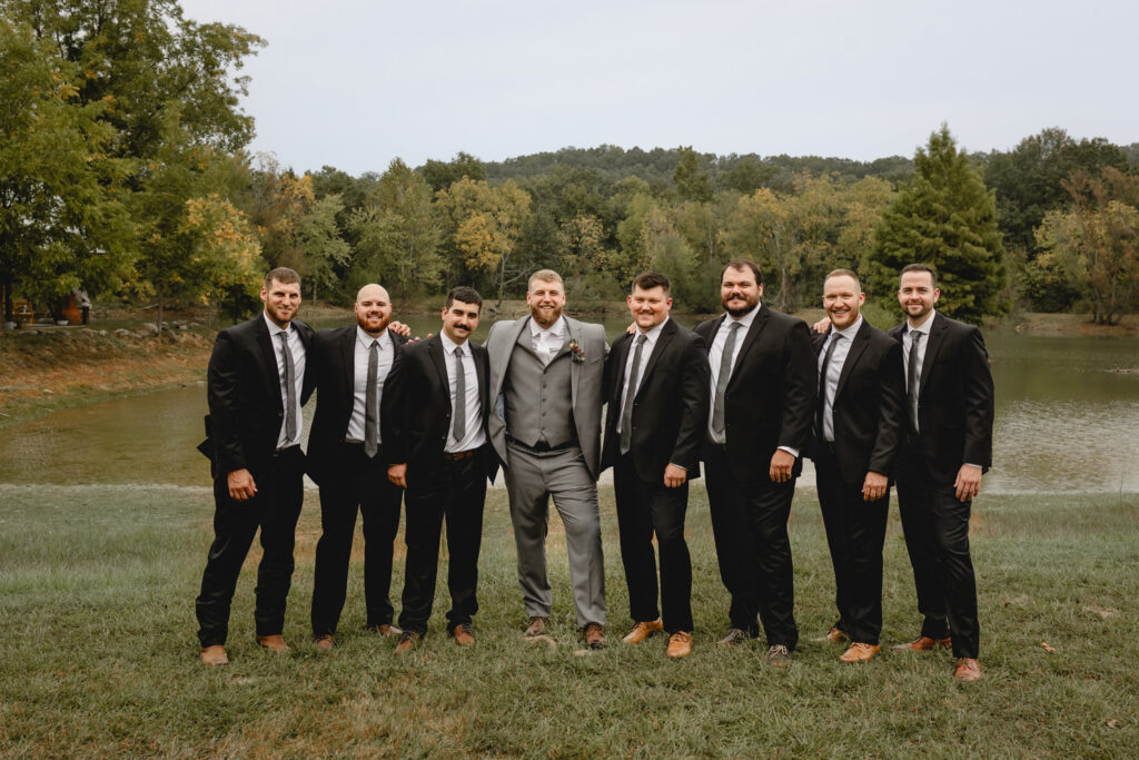 Groomsmen and groom posing at the water near a lake