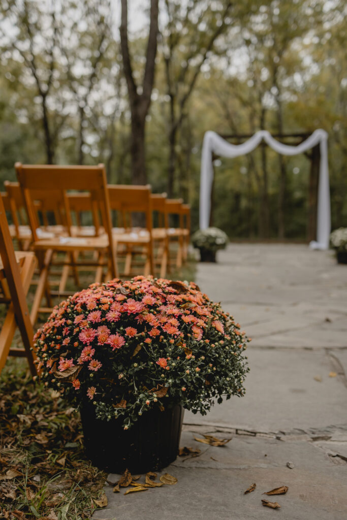 Pink mums with wooden chair and arbor at lost hill lake wedding venue
