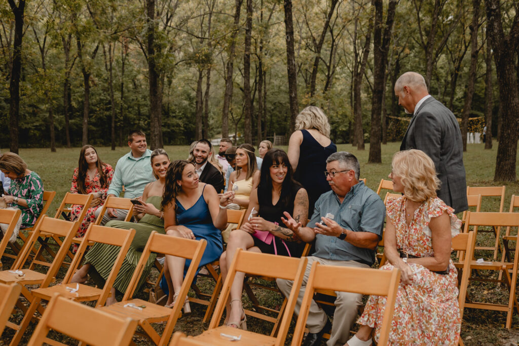 Wedding guest sitting in wooden chair visiting and laughing.