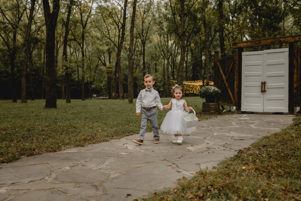 Child ring bearer and flower girl holding hands and walk down aisle
