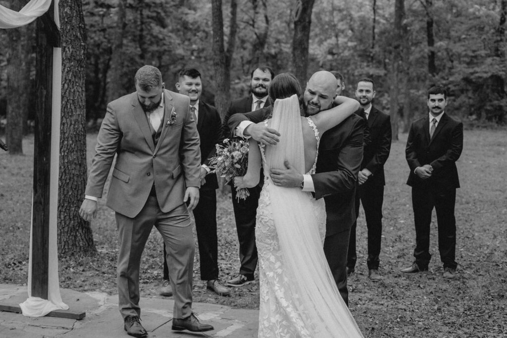 Bride and her brother embrace during wedding ceremony
