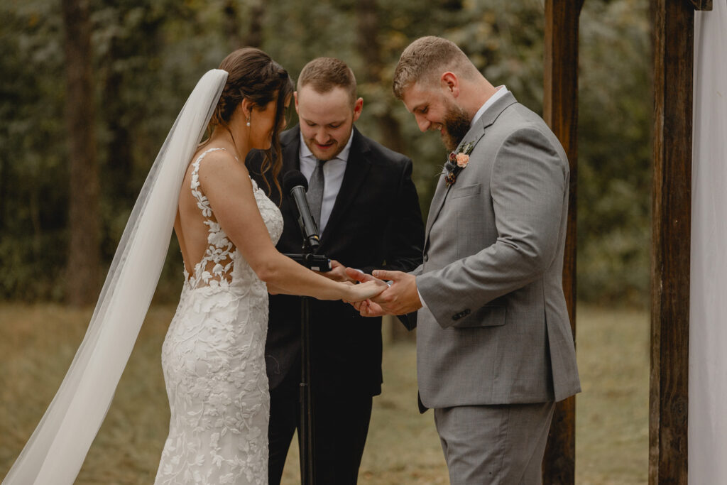 Bride and groom hold hands at alter during outdoor wedding ceremony.