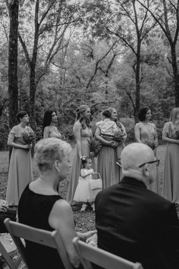 Bridesmaids smiling and looking on during wedding ceremony.