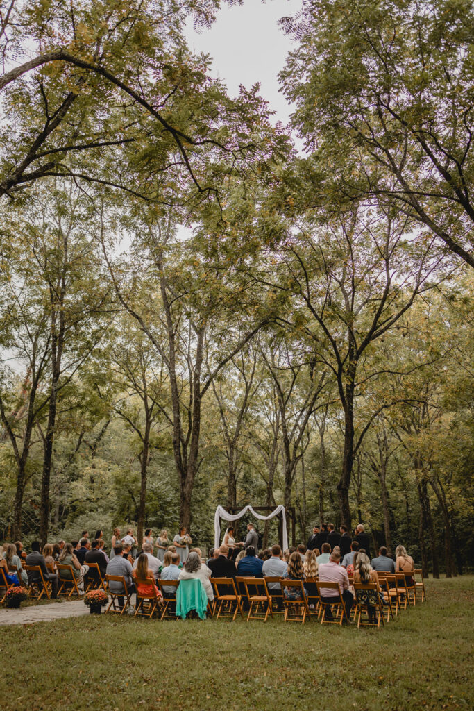 Wide shot of wedding ceremony in outdoor walnut grove.