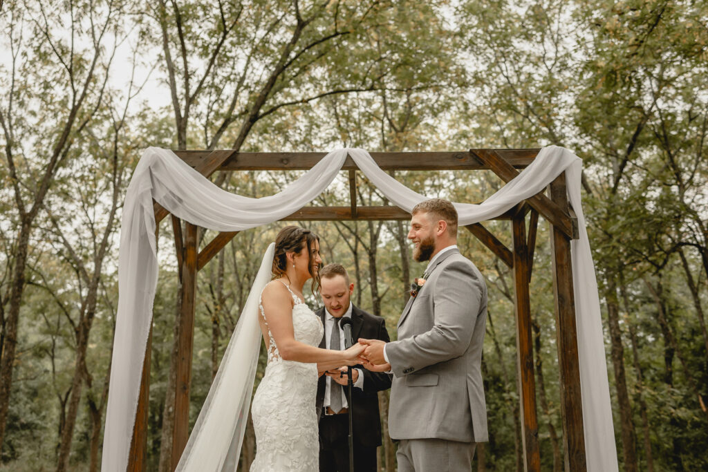 Bride and groom at alter holding hands in outdoor ceremony in a walnut grove