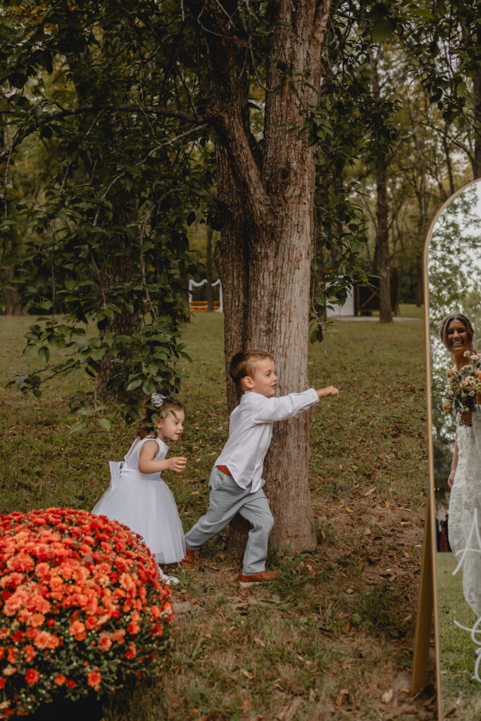 Small children playing near a tree at a wedding.