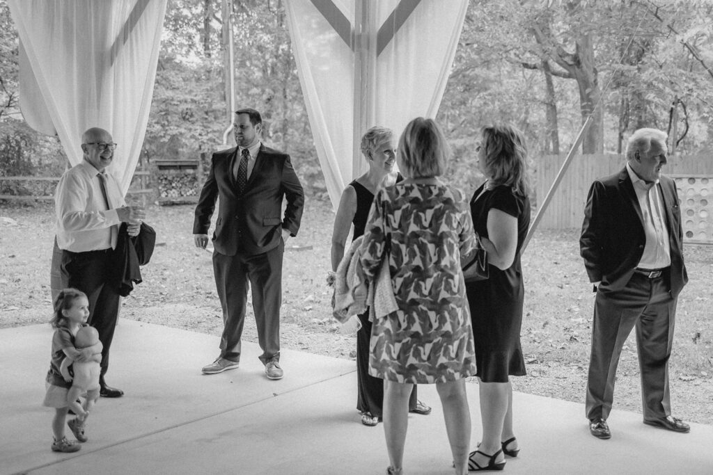 Guest standing and visiting at wedding reception in outdoor gazebo.