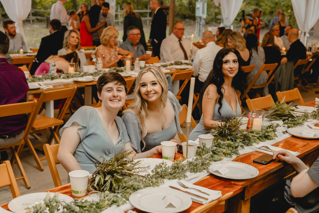 Bridesmaids pose for candid photo while seated at table.