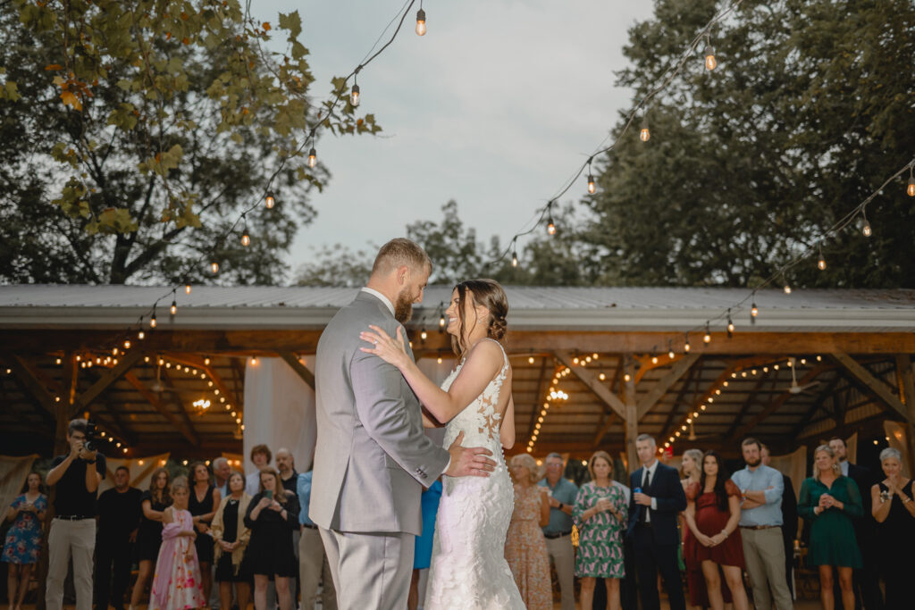 Bride and groom sharing their first dance in front of wedding reception pavilion.