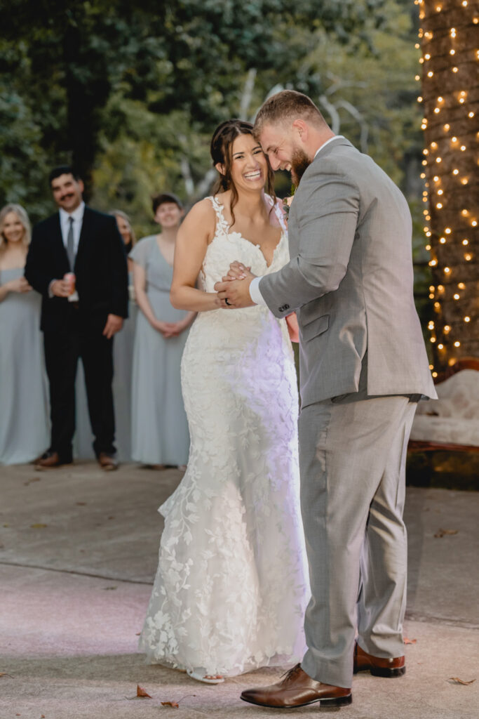 Bride laughing while dancing with her new husband at outdoor reception.
