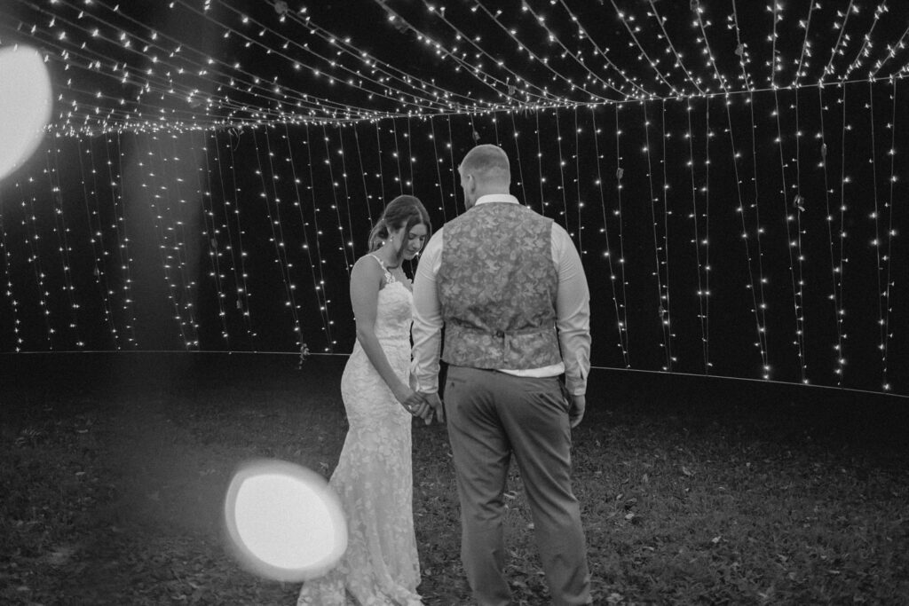 Bride and groom posing under string lights