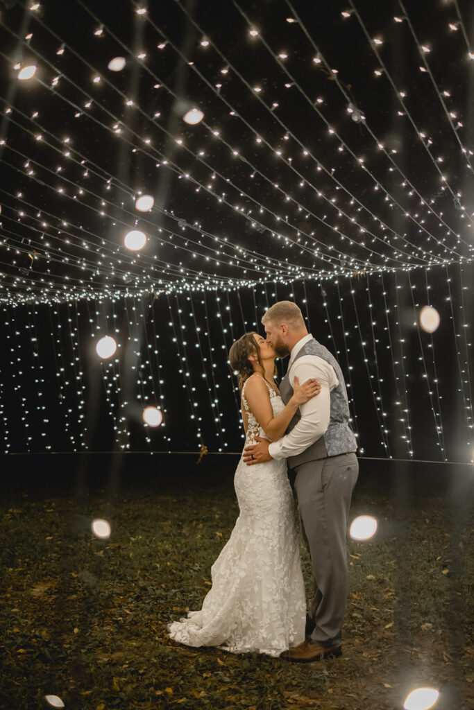 Bride and groom sharing a kiss under lights at lost hill lake.