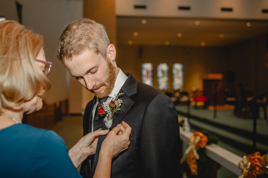 mom pinning boutonniere on her son the groom