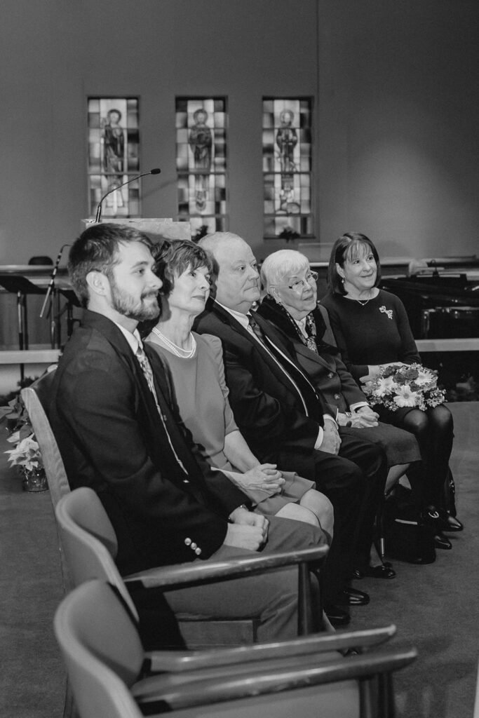 black and white shot of family loving watching a wedding ceremony in a church