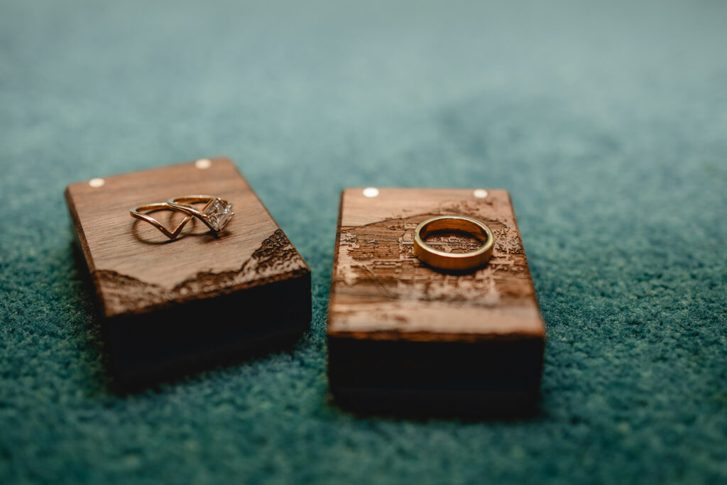 close up of two engraved wooden ring boxes, one with the bride's golden rings on top and the other with the groom's